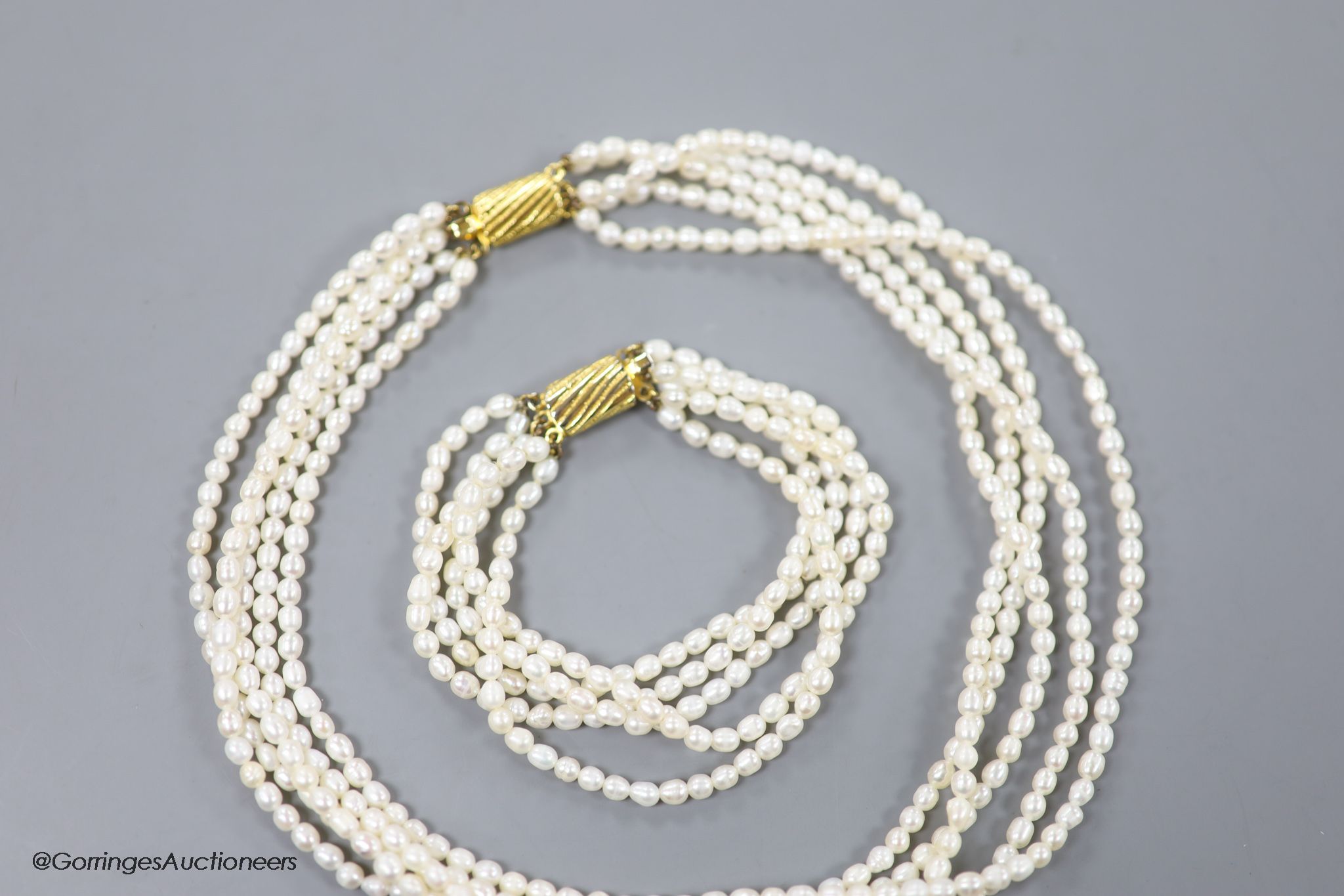 A modern multi strand cultured pearl necklace, with gilt metal clasp, 38cm and a matching bracelet, 17cm.